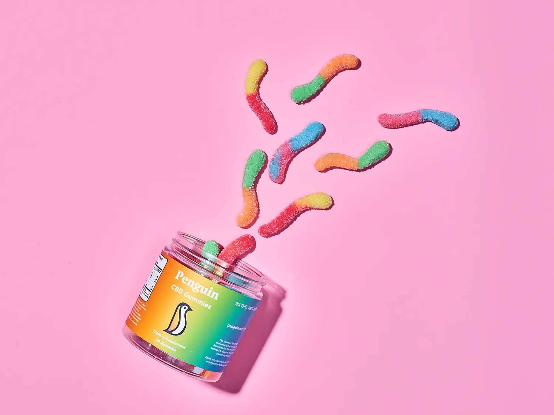 Penguin CBD Jar of colorful gummy worms on a pink background